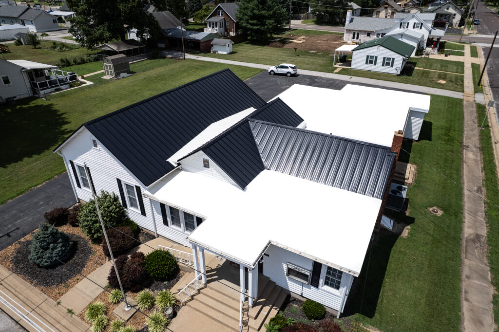 Aerial view of a commercial roofing project featuring a newly installed black standing seam metal roof on a commercial building, showcasing durable metal panels, professional craftsmanship, and a long-lasting commercial roofing system.