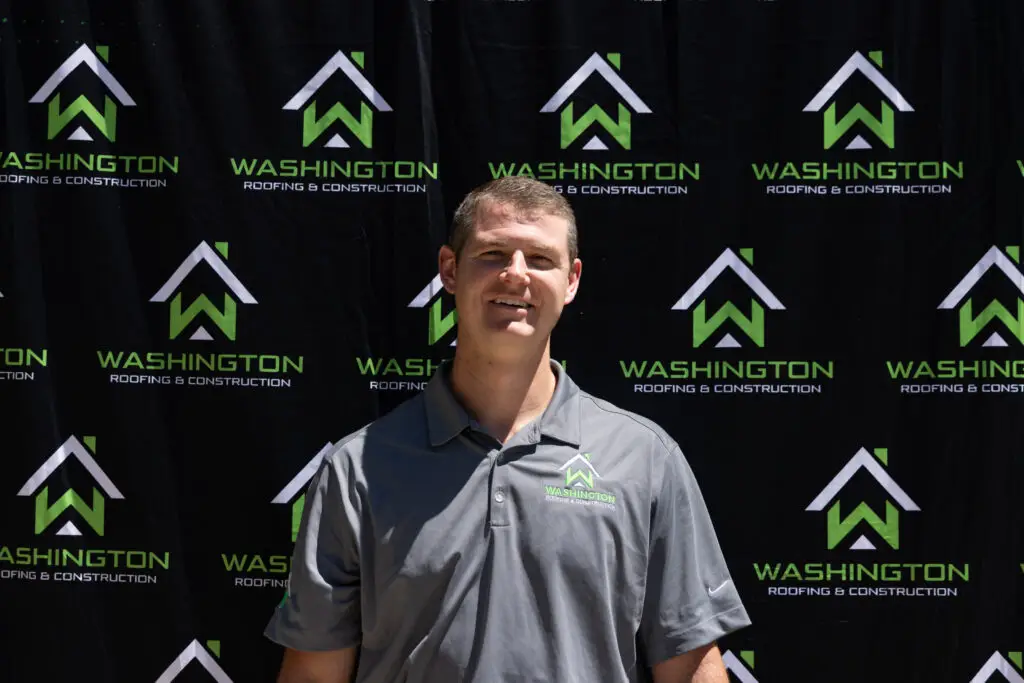- Washington Roofing & Construction team member Kristian Foster - Sales team. standing in front of a backdrop featuring the logo and name "Washington Roofing & Construction.