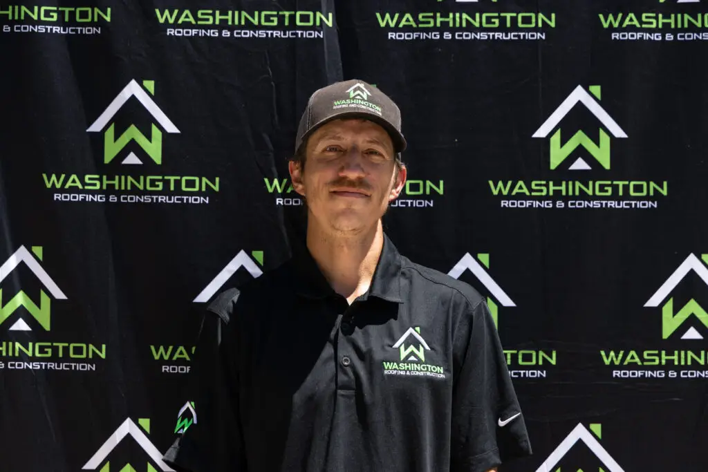 - Washington Roofing & Construction team member Perry Nassif - Sales team. standing in front of a backdrop featuring the logo and name "Washington Roofing & Construction.